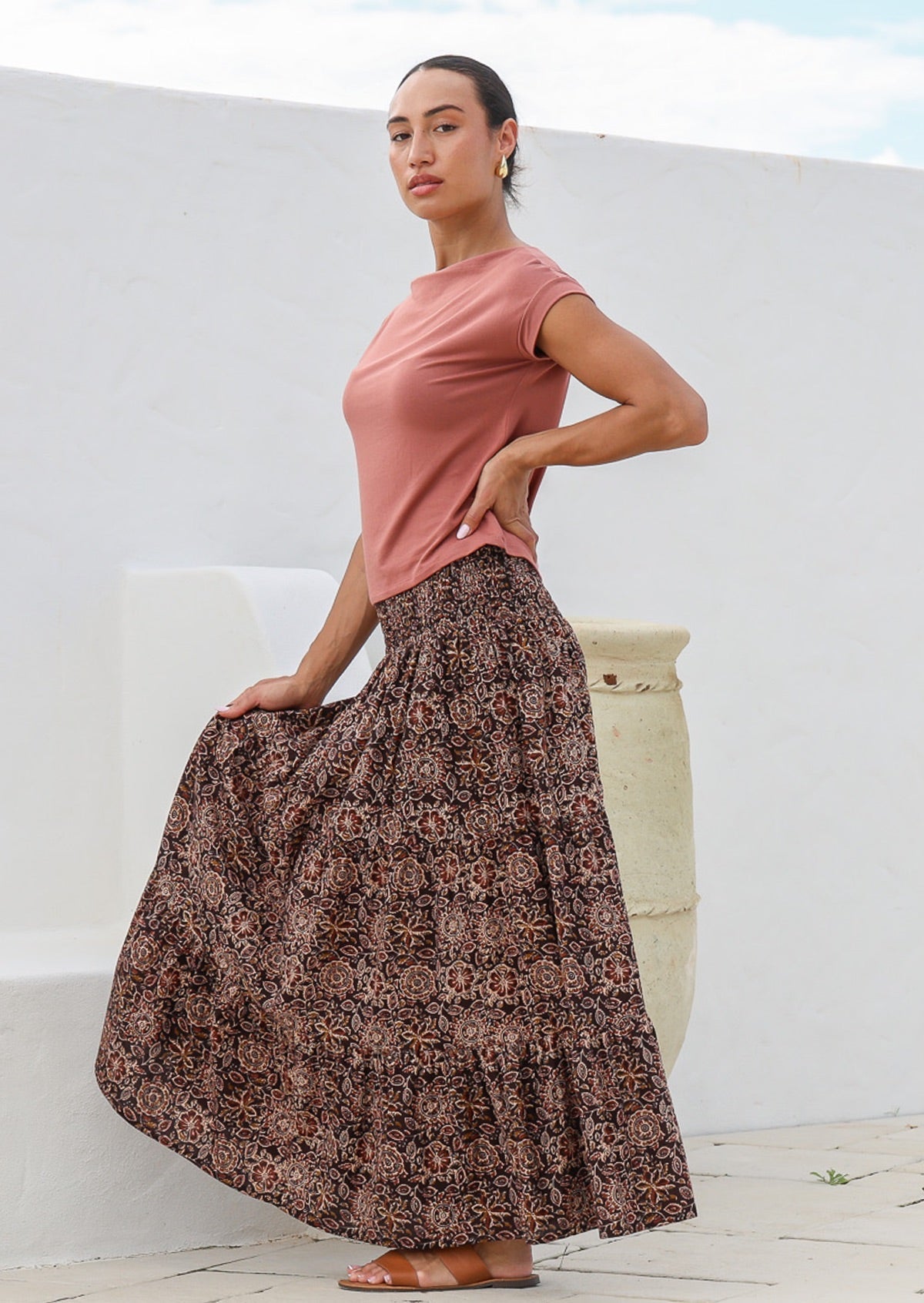 Model stands on side wears 100% cotton tiered maxi skirt with wide elasticated waistband and beautiful florals on brown base.
