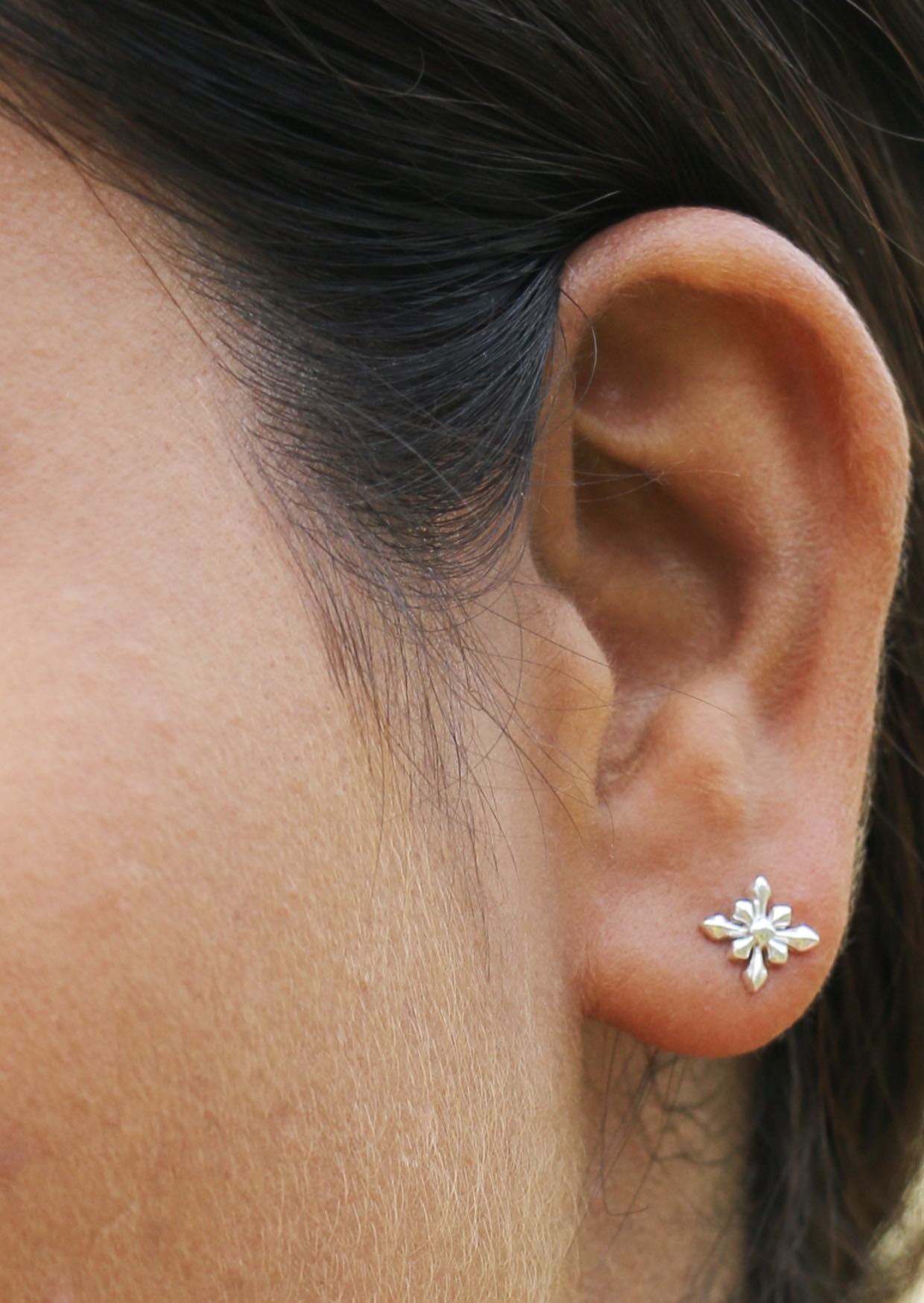 Woman wearing a nature inspired silver starflower studs with smooth polished finish 