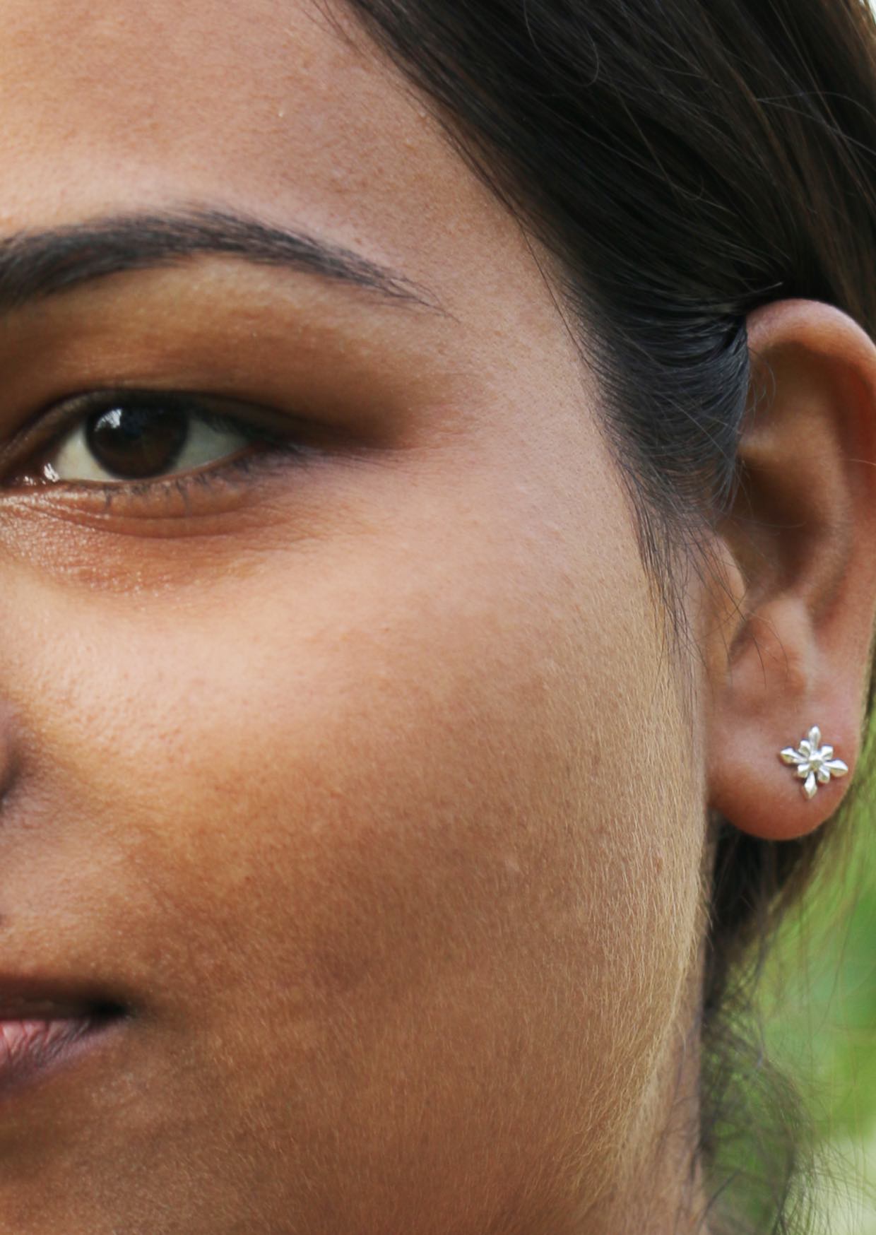 Close up of a person wearing a silver  starflower studs with secure butterfly backs