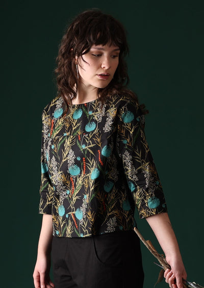 Model wears botanical print with pops of teal on a black base cotton top