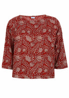 Front view of red based floral top with round neckline and 3/4 sleeves
