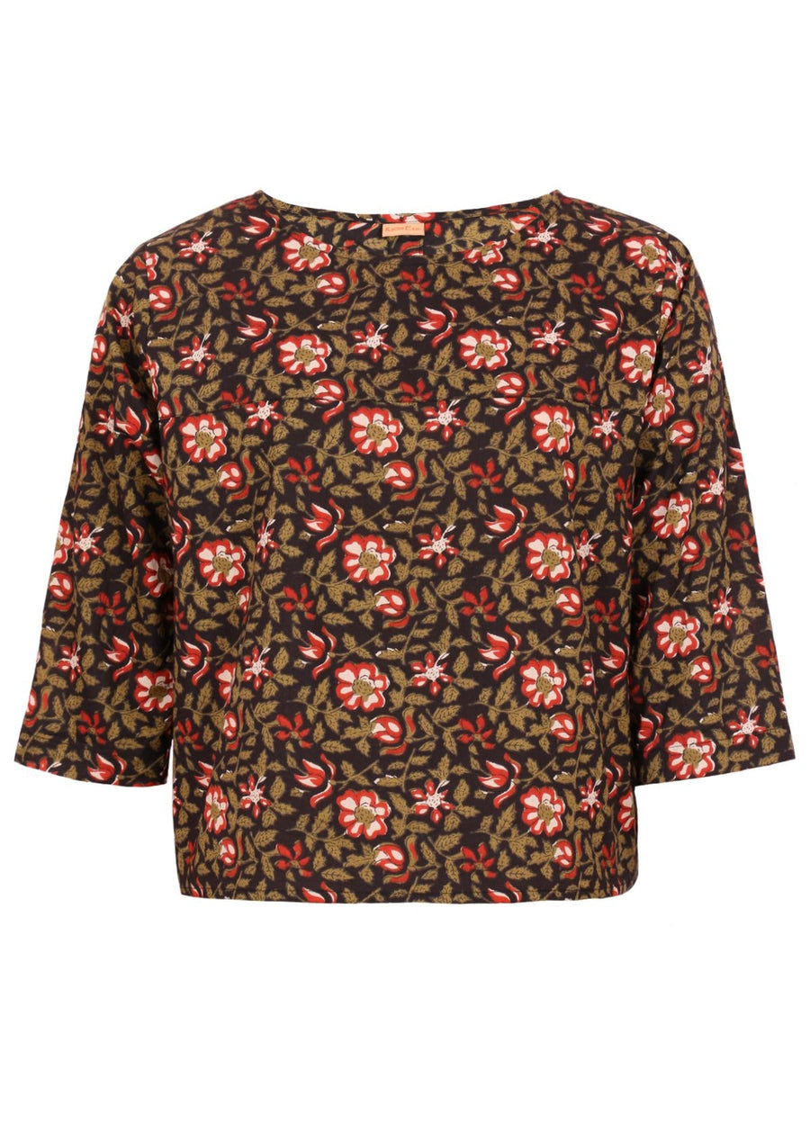 woman with dark hair and red lipstick in boxy cotton blouse, black with floral design 