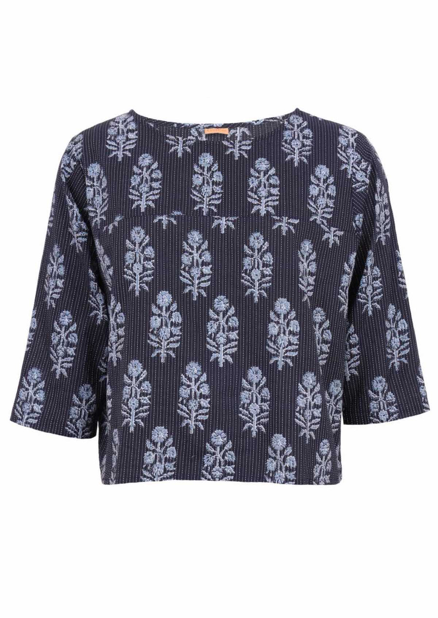 Woman with dark hair in navy blue boxy style blouse with 3/4 sleeves
