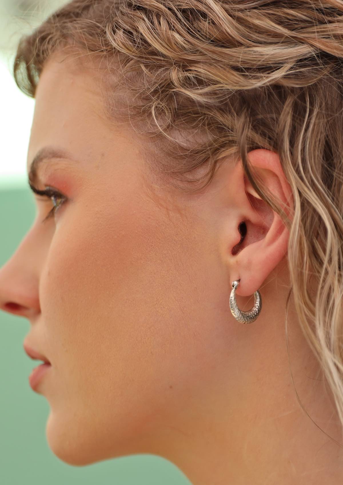 blonde haired woman wearing earthy silver hoops