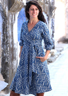 model wearing blue cotton wrap dress with hands in pocket
