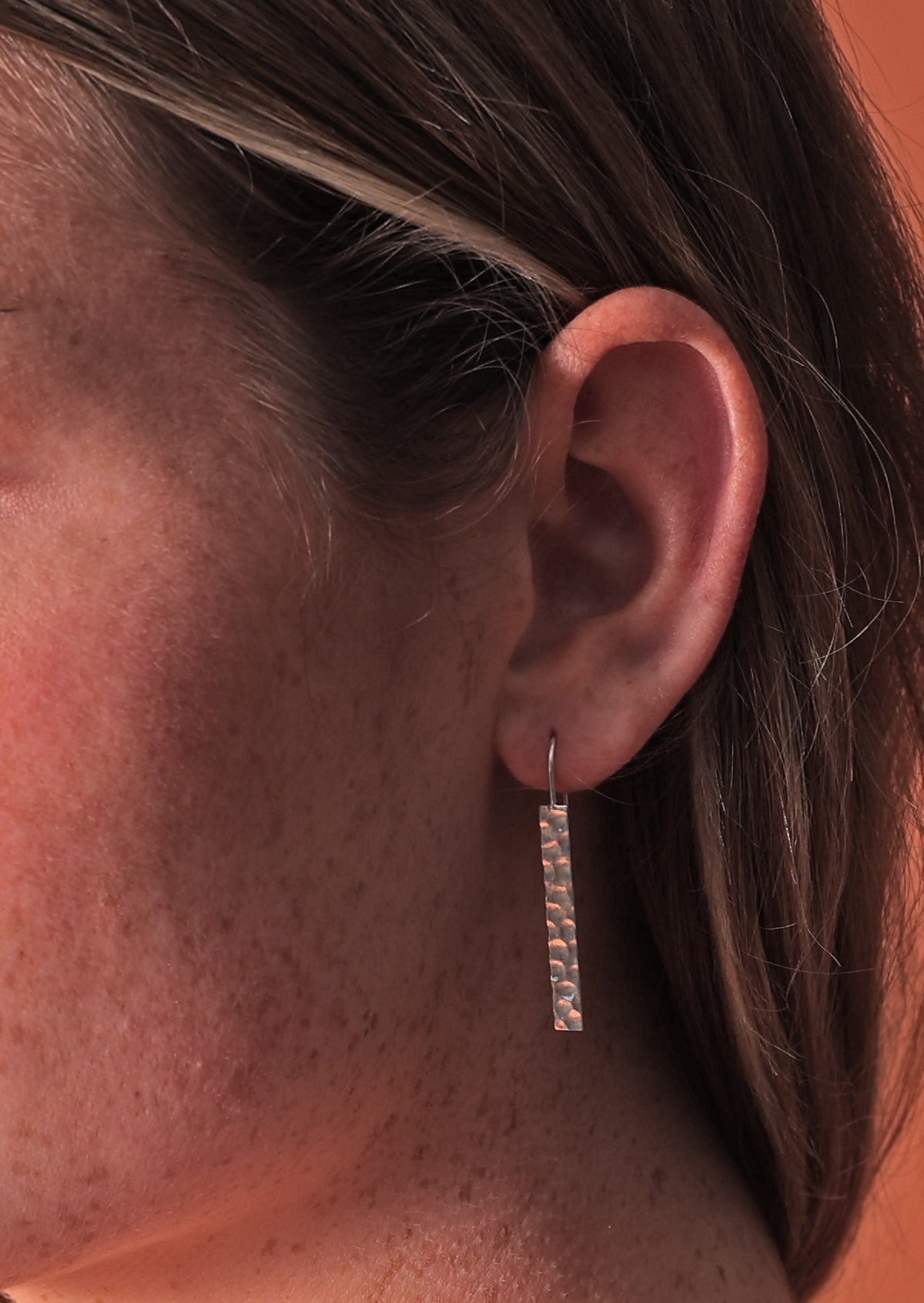 woman's ear with modern hammered silver earring