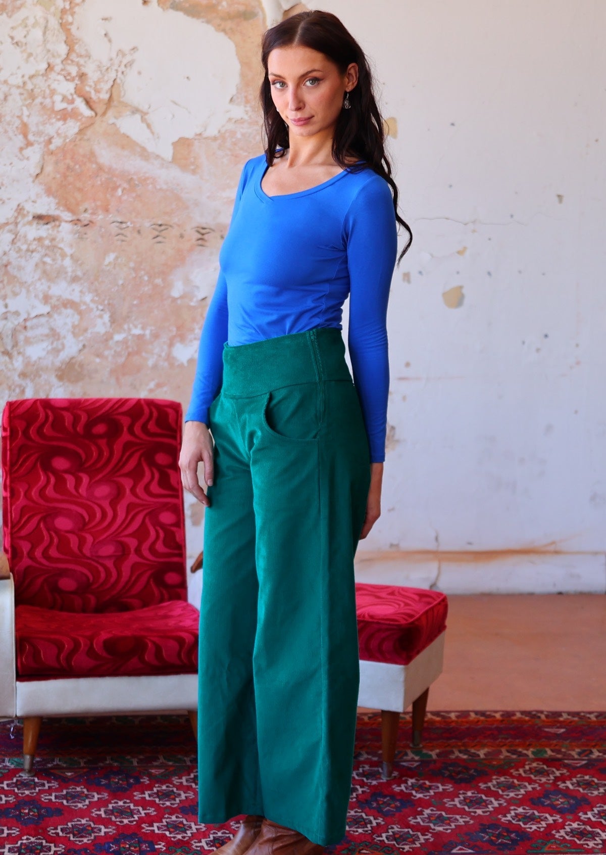 Woman wears electric blue long sleeve top with teal wide leg corduroy pants with a wide waistband and side zip