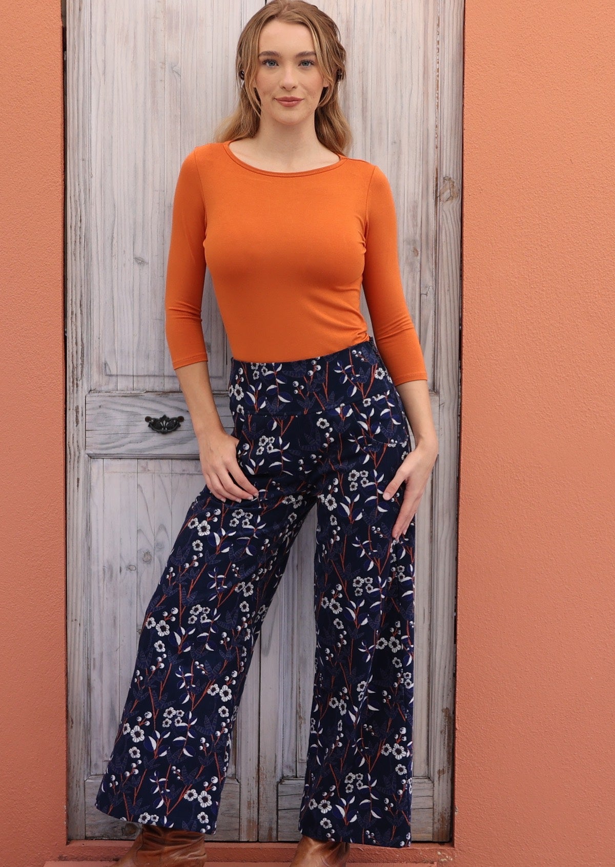 Model poses in cotton corduroy wide leg pants paired with a brick orange stretch top.