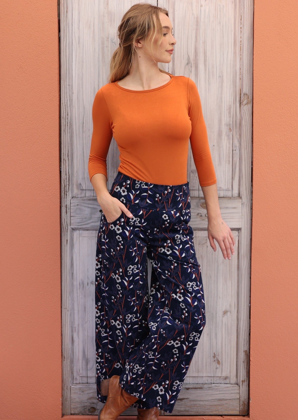 Woman pairing a beautiful wide leg, floral printed cord pants with orange stretch rayon top and boots.