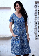 Woman wears cotton V-neck relaxed fit dress with empire waistline and short sleeves