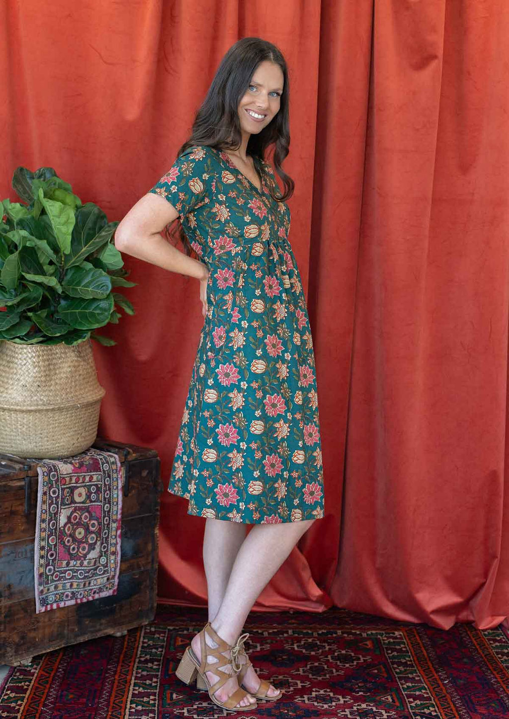 Model stands sideways wearing a cotton V-neck relaxed fit dress with empire waistline and short sleeves.