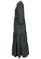 Side view of a full length maxi dress with 3 tiered flowy skirt, mandarin collar, buttoned bodice and pockets