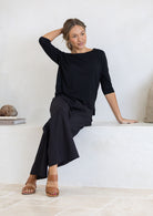 Woman wearing a black stretch rayon top paired with black cotton pants sitting on a bench