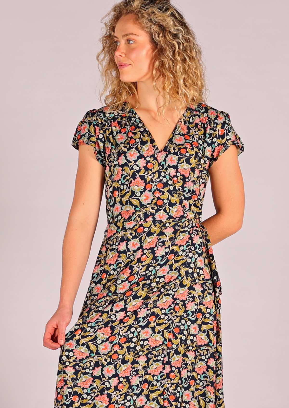 close up of model standing holding one side of skirting of navy floral rayon wrap maxi sundress 