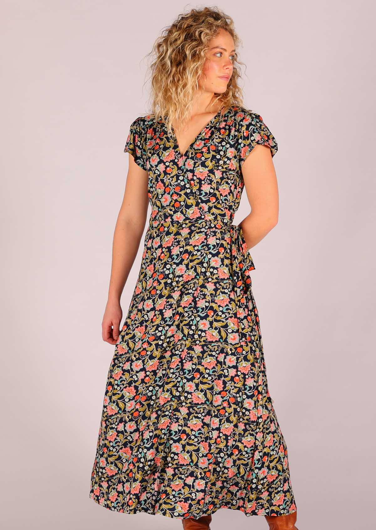 Model looking to the side standing with hand behind back wearing navy floral rayon wrap maxi sundress 