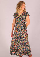 Model looking to the side standing with hand behind back wearing navy floral rayon wrap maxi sundress 