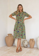 Woman wearing a green based floral print, 100% cotton dress.