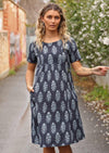 Woman in lane way with navy blue cotton Indian print summer dress with hand in pocket