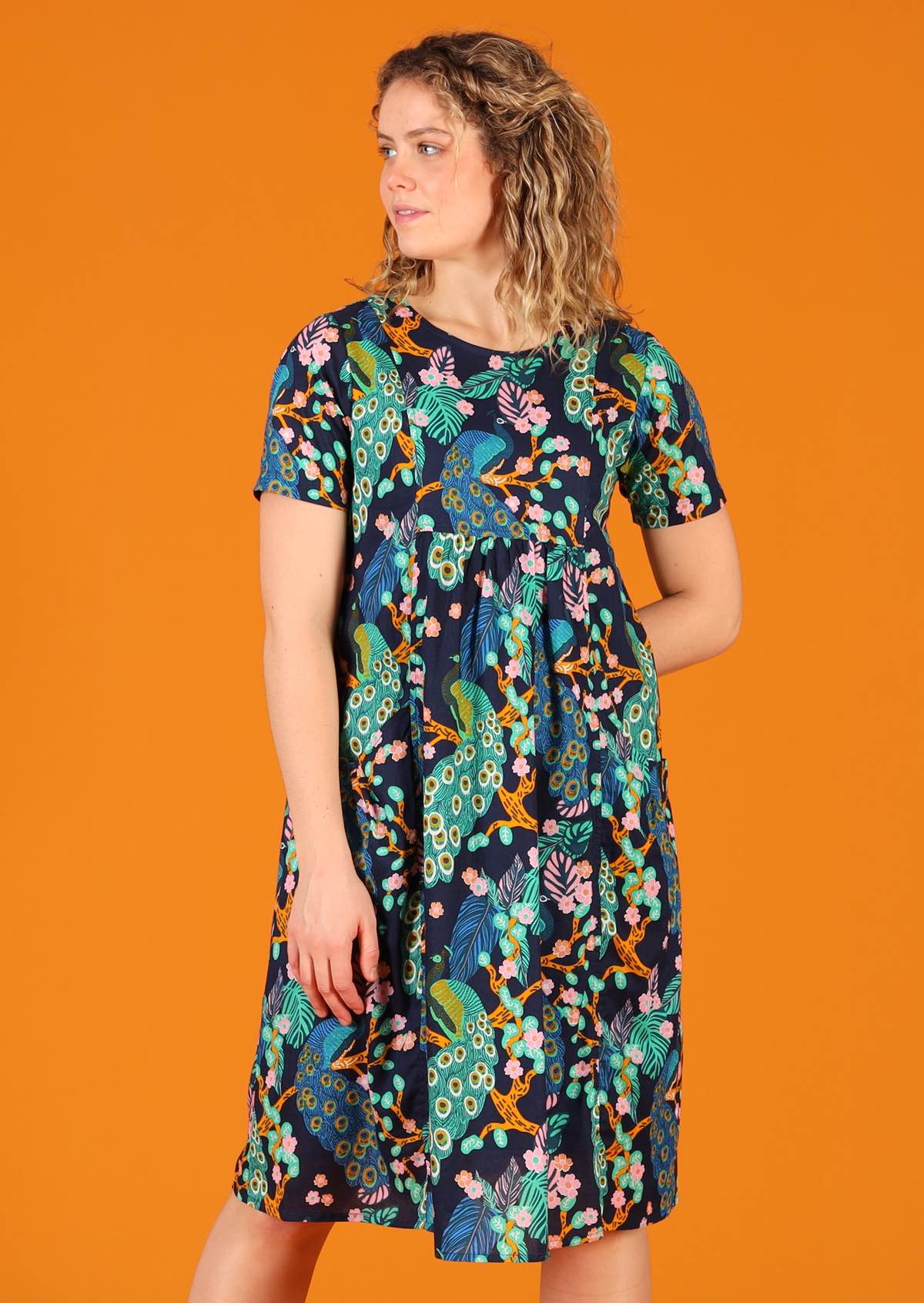 Woman wearing knee length lightweight cotton peacock print dress