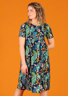 Woman wearing knee length lightweight cotton peacock print dress