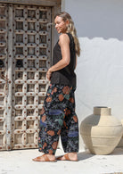 Woman wearing a black sleeveless top and floral wide leg cotton pants with elasticated waist, pockets and pleated ankles