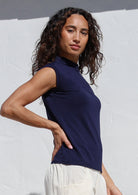 Woman wearing a navy sleeveless top against a white background