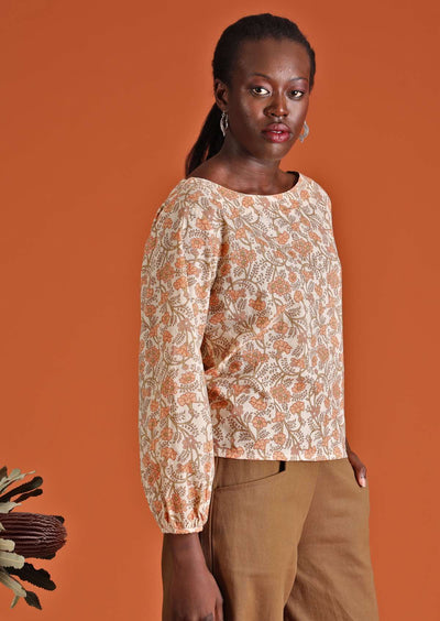 Model in cotton floral women's top, cream with apricot coloured flowers worn over khaki cotton pants