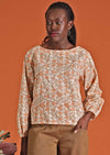 Model in cotton floral women's top, cream with apricot coloured flowers worn over cotton pants