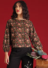Model with dark hair and red lipstick in Isla Top Wild Rose black floral  top