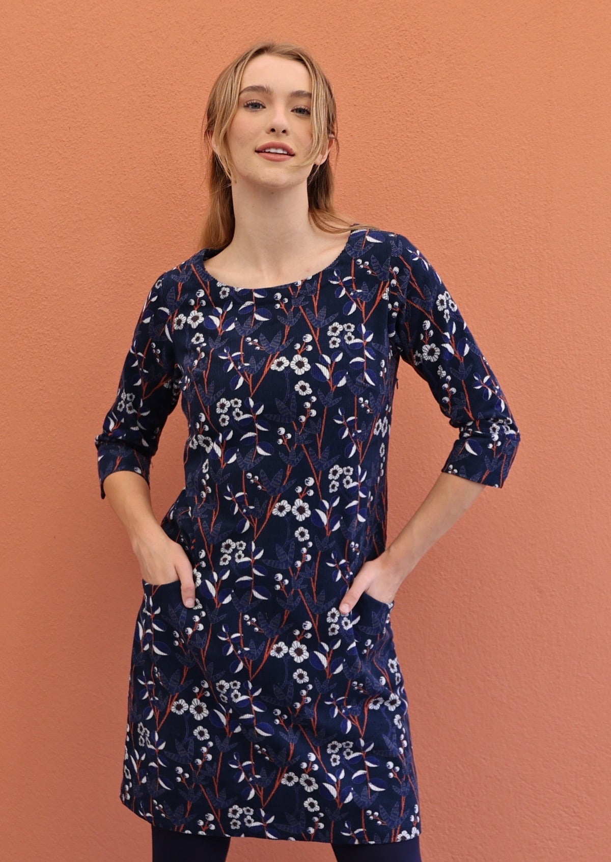 Woman posses in beautiful white, orange and blue floral printed corduroy dress.