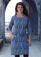 Woman standing and smiling with hand in pocket wearing 100% cotton blue and white dress 