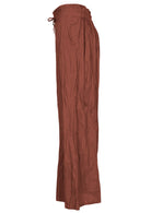 Side view of lightweight wide leg cotton pants in rust shade with drawstring waist tie and elastic back waist