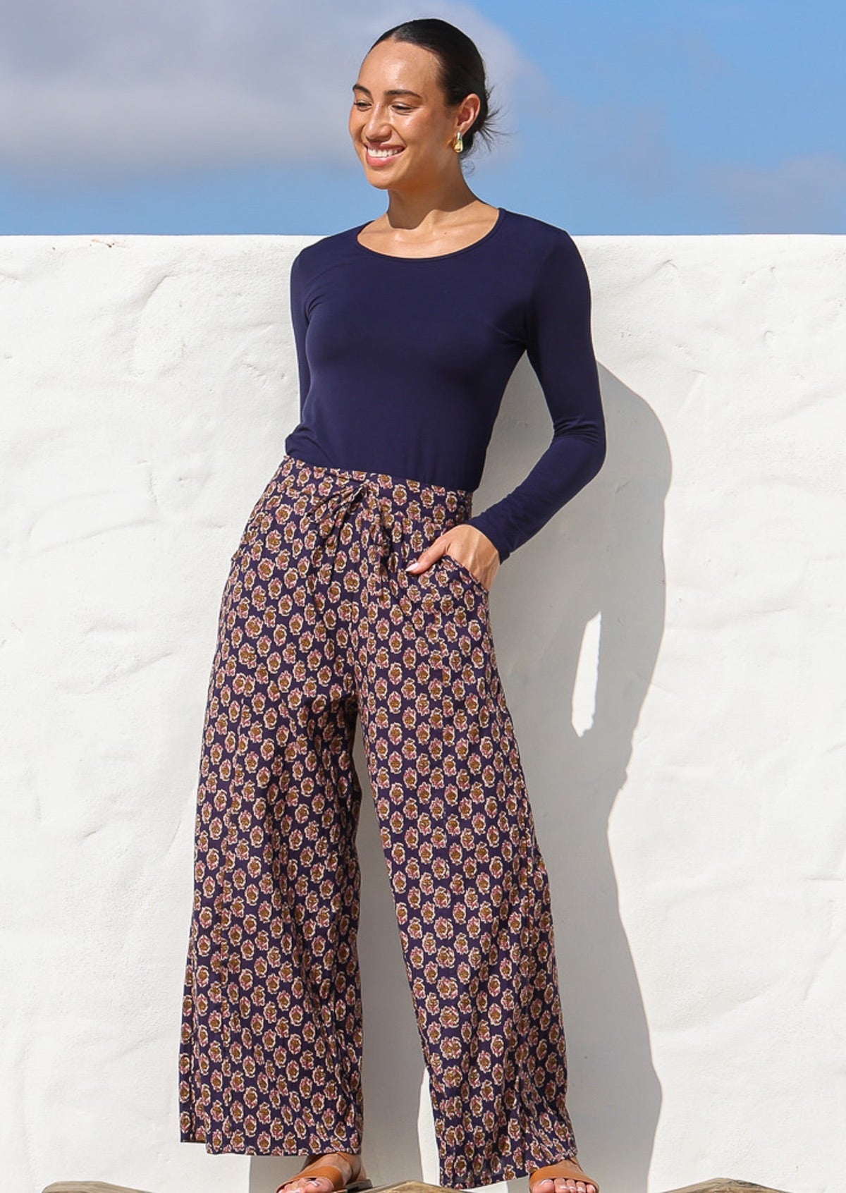 Model wears wide leg high waisted cotton pants with drawstring and a hand in pocket.