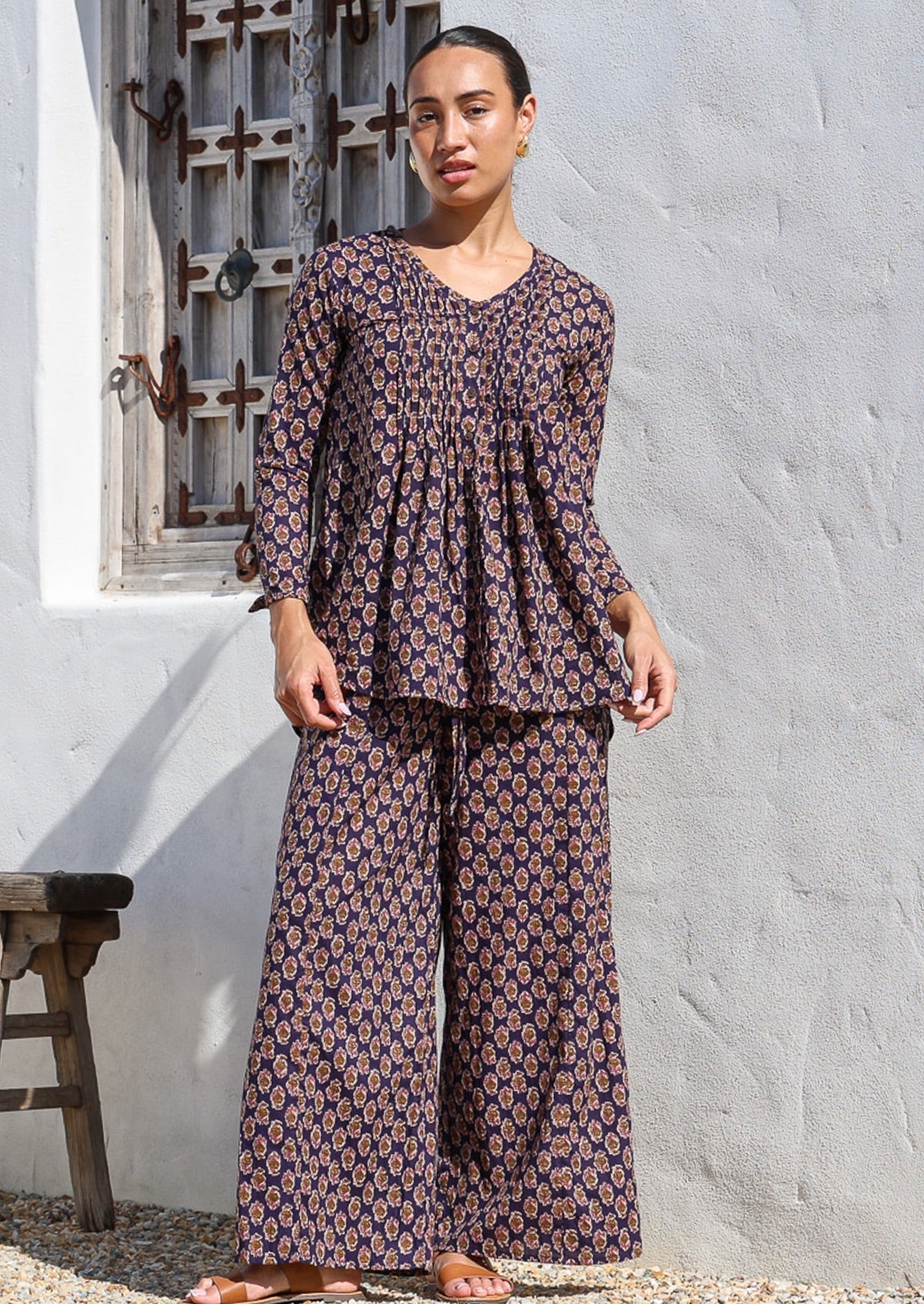 Model wearing wide leg cotton pants in dark purple with a shirt style long sleeved cotton top. 