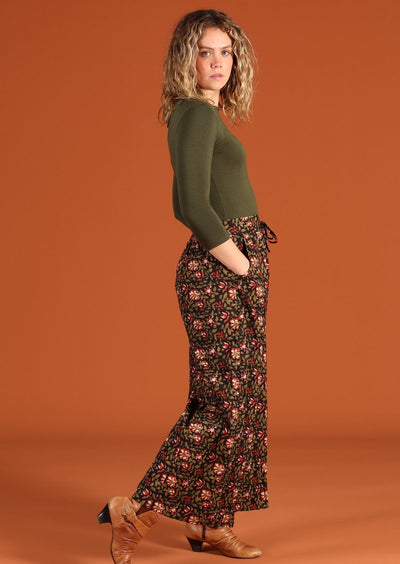 side view of model in Janis Pants Wild Rose wide legged cotton women's pant with pockets and long sleeve army green top