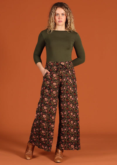 Blonde haired model in Janis Pants Wild Rose wide legged cotton women's pant with pockets and long sleeve army green top