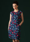 Model wears knee length dress in a blue fruit print.