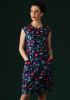 Model wears a navy based dress with a pink and red fruit print.