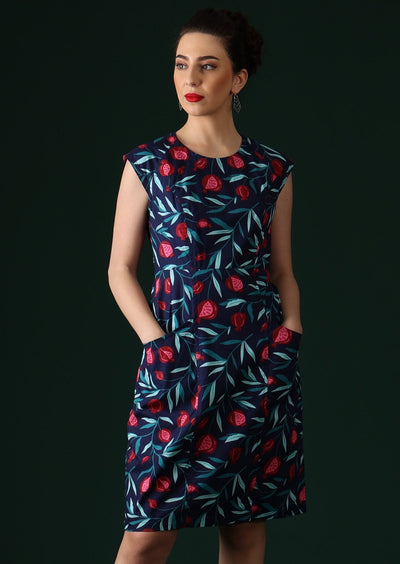 Model wears a navy based dress with a pink and red fruit print.