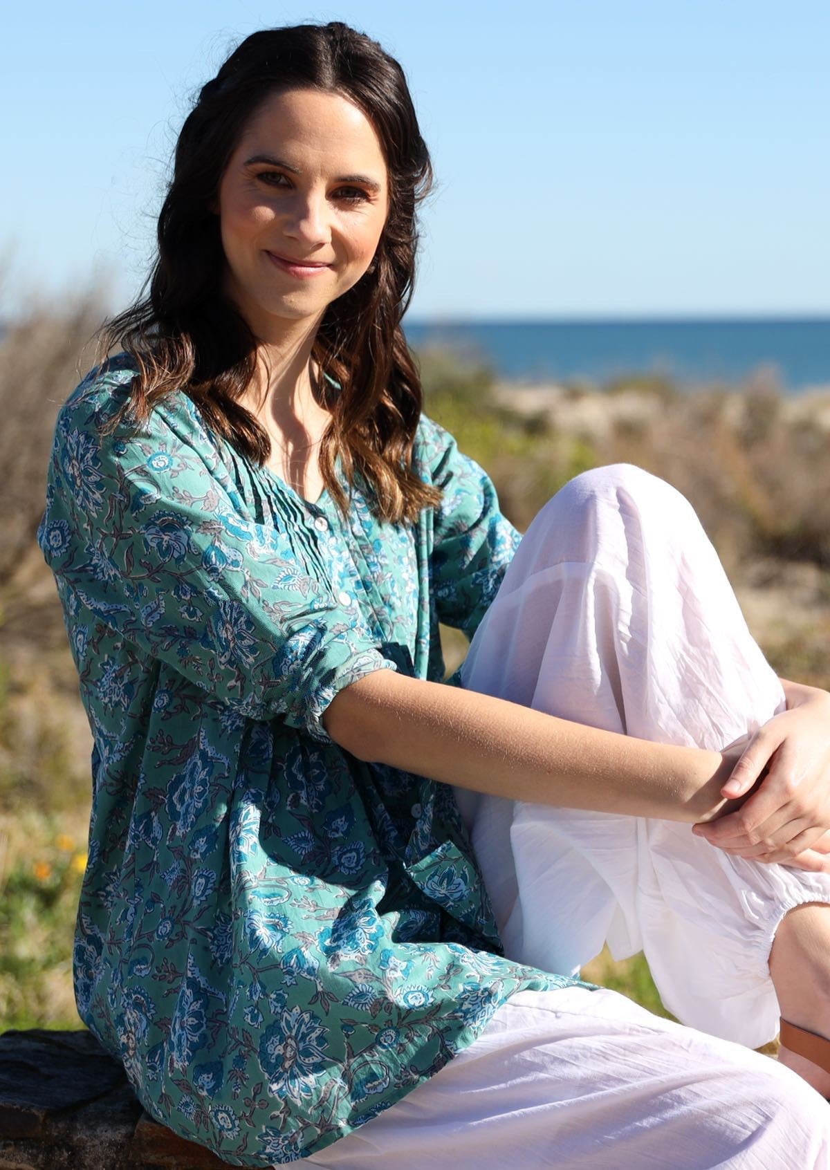 Woman wears cotton long sleeve top with small pin tucks across front and back of bodice, in floral print.