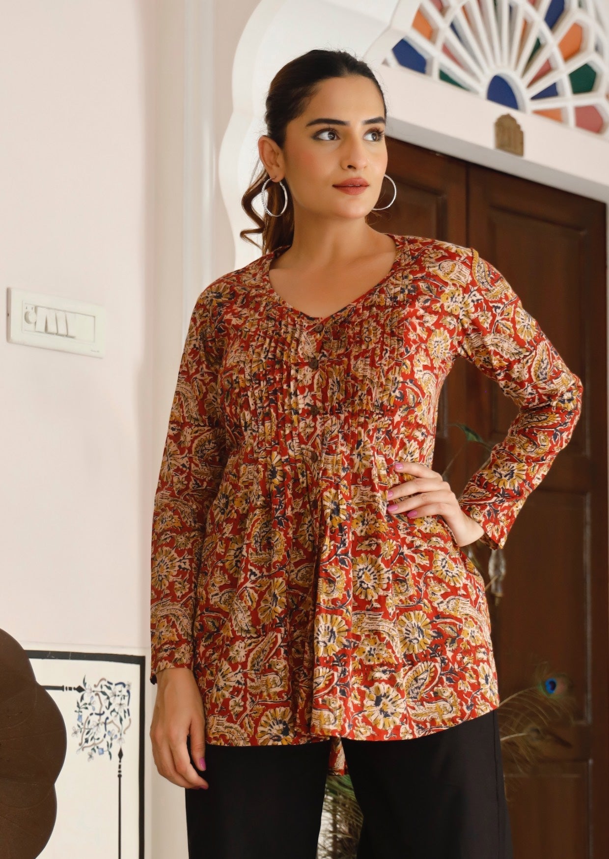 Woman poses in cotton long sleeve button through top with small pin tucks across chest in floral print with rusty base.