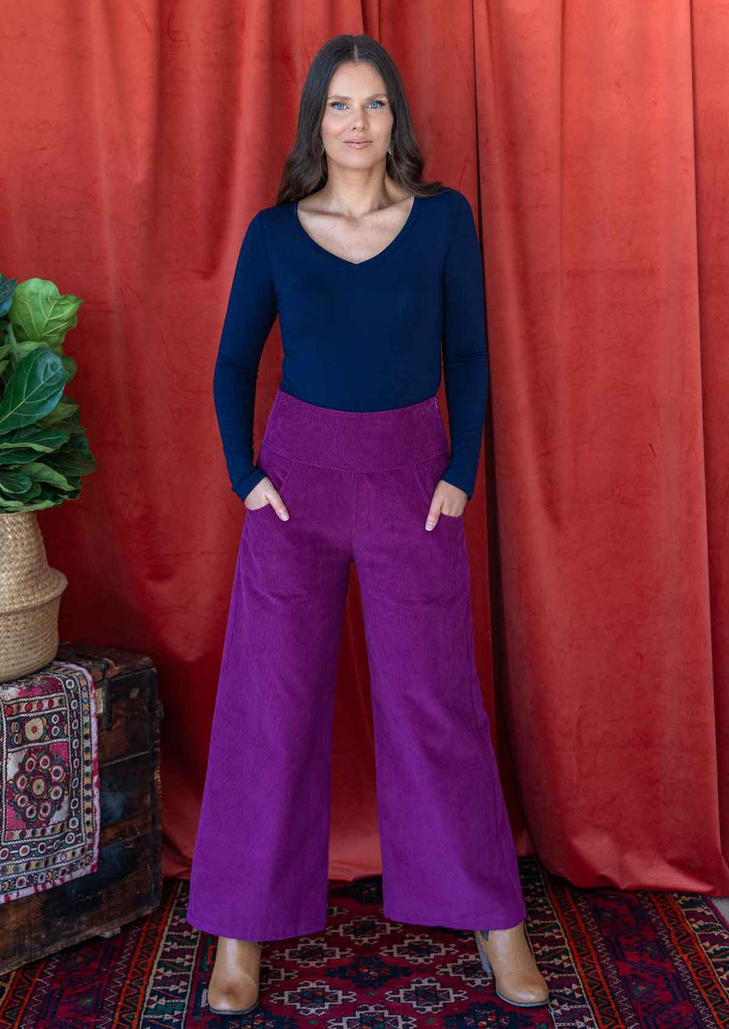 woman wearing deep v-neck navy blue long sleeve stretch soft rayon top with purple corduroy pants 