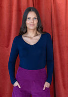 woman wearing navy blue long sleeve stretch v-neck soft rayon with purple corduroy pants 