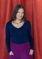 woman wearing deep v-neck navy blue long sleeve stretch soft rayon top with purple corduroy pants 