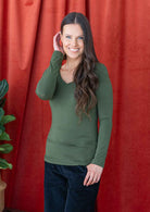 woman wearing long sleeve stretch top in green with v-neck over black corduroy pants 