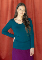 Woman wearing a teal long sleeve stretch v-neck soft rayon top with purple corduroy skirt 