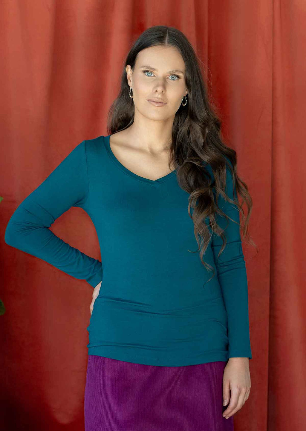 Woman wearing a teal blue long sleeve stretch v-neck soft rayon top