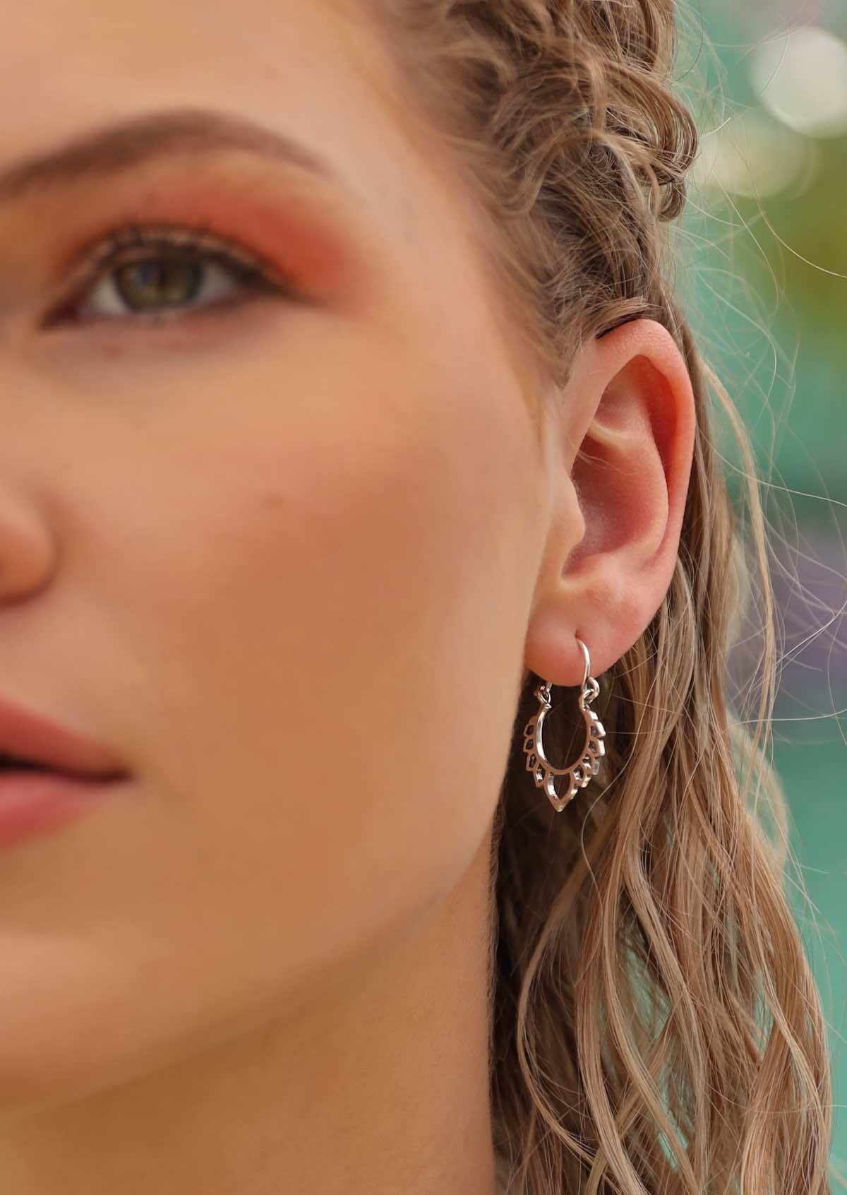 model wearing small silver lotus hoops