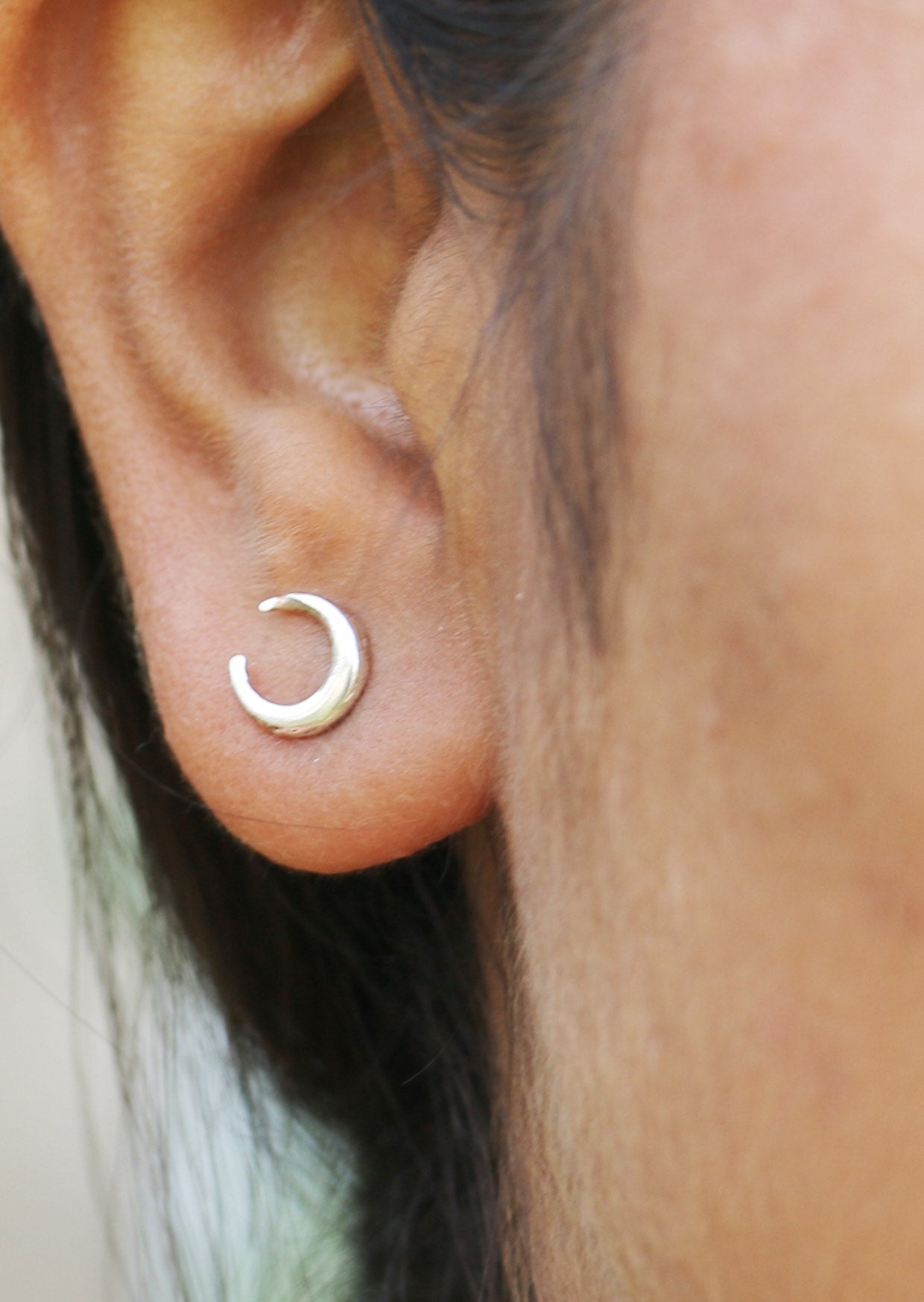 Close-up of an ear wearing a elegant sterling silver Luna Love studs with a crescent moon design