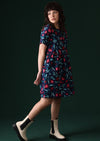 Model wears dress with high round neckline and pockets.